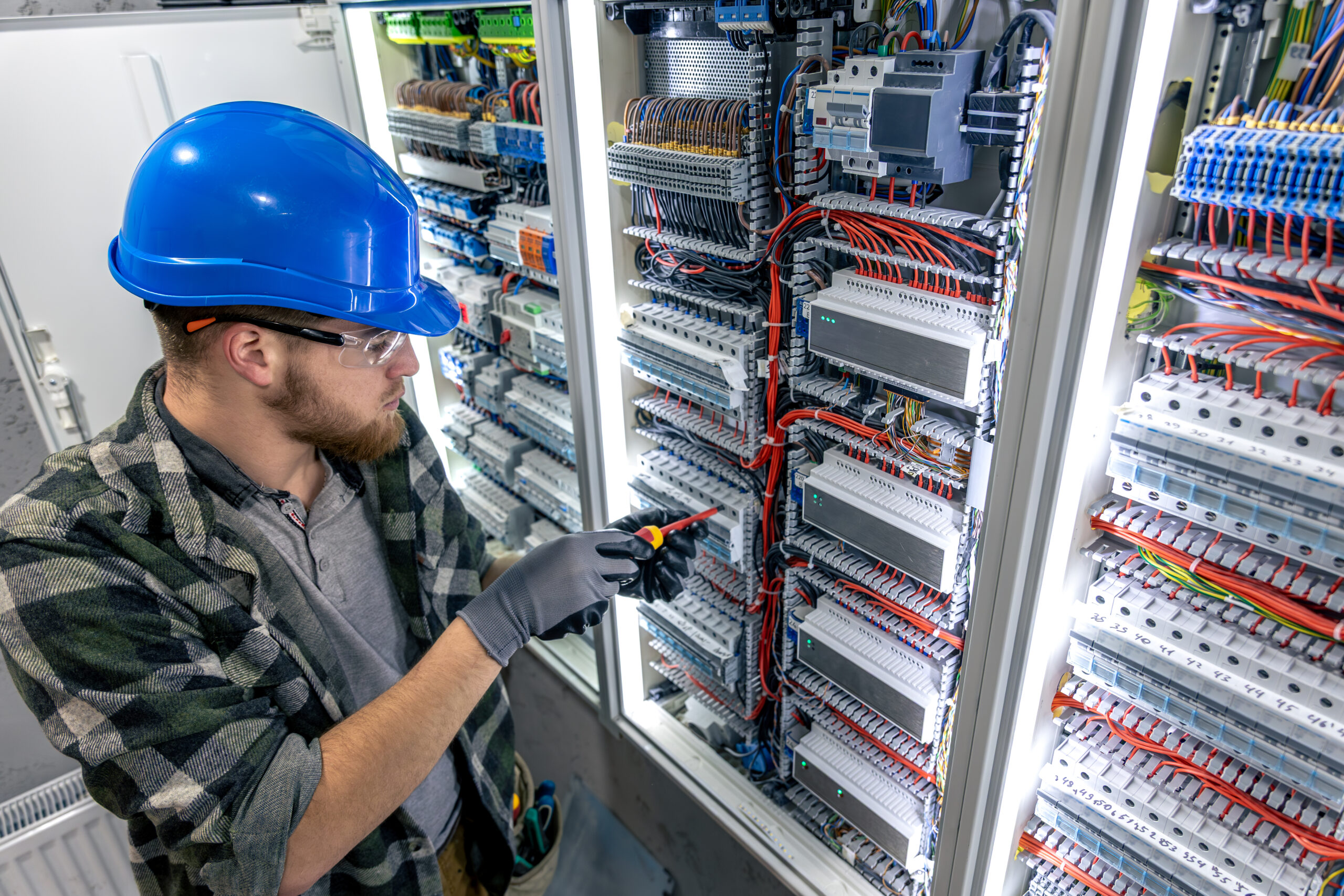 A man in protective gear stands in front of an electrical panel with a screwdriver in hand, ready for technical work. SSUCv3H4sIAAAAAAAAA41Py46DMAz8F59BSiCVCr9S9RASl1oFUiVmqxXKv69DqfbanOYRe8YbkIcerFLamE7VRpum1vqm6sE1TW3arj2d2g7tzUMF3jJCr9uituasm7NqlLwKBpvIQb8BTdOaOFqmsEAvTsTFY9wheuIQyU7CcgWJLa8Jk4wJc7J7FHfnn32XrehSUMLTOhSQqy+1awV2xMX9lv25FJnQ7nEXsR4vxjgf2YHvpWKBz0iOlvHoJKeE+Y2XwGV2T+DgHuSP4fcZdxI1lixYn1OwHv1hr8NMzB8a8Yfw9f875/wHtTXq8YQBAAA=